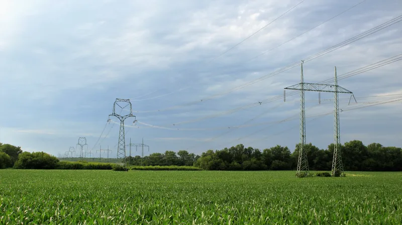 An image showing three transmission towers in a grassy field